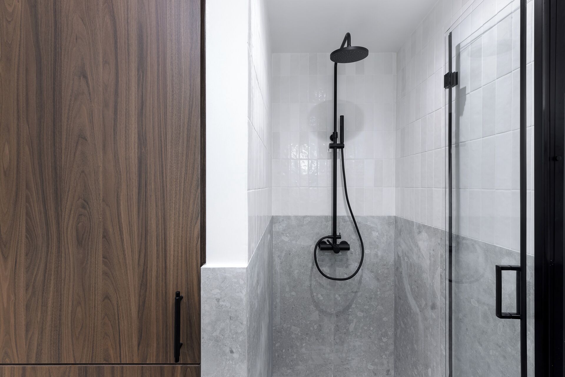 A modern bathroom with a shower, tiled walls, and a wooden door.