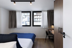 Una habitación de hotel con cama, escritorio y armario.
