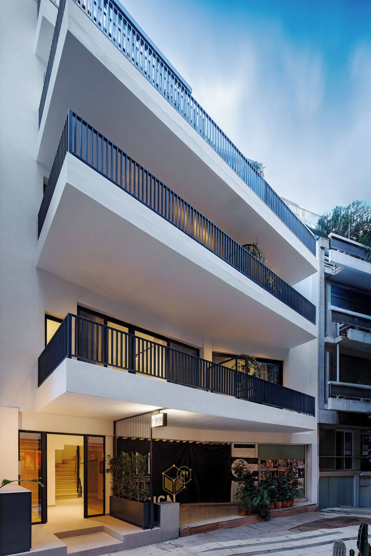 A modern multi-story building with balconies and a storefront.