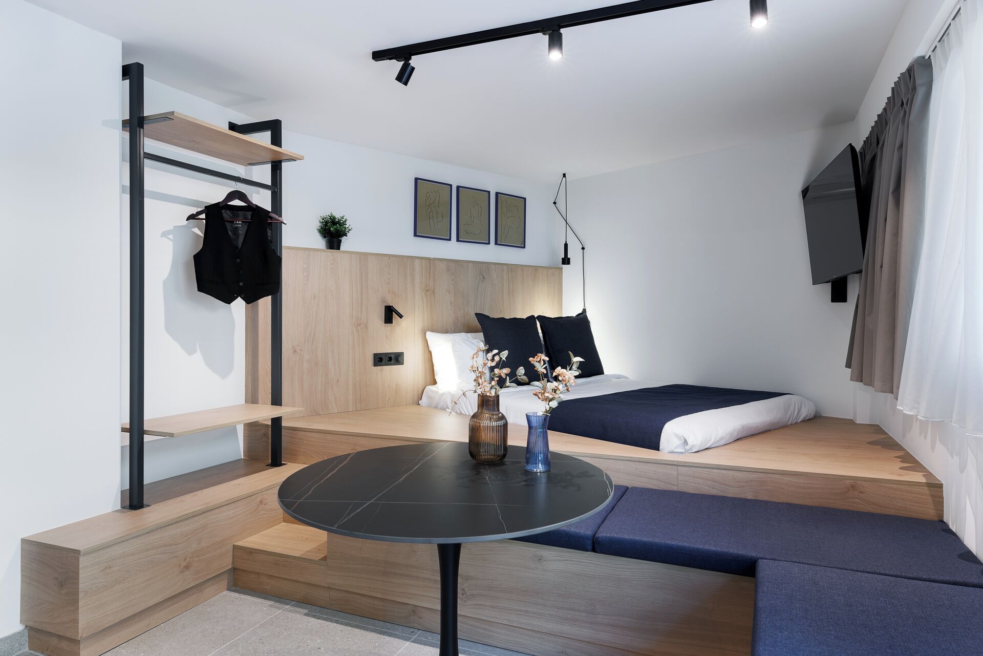 Ein modernes, kleines Schlafzimmer mit Bett, Nachttisch und einer kleinen Sitzecke.