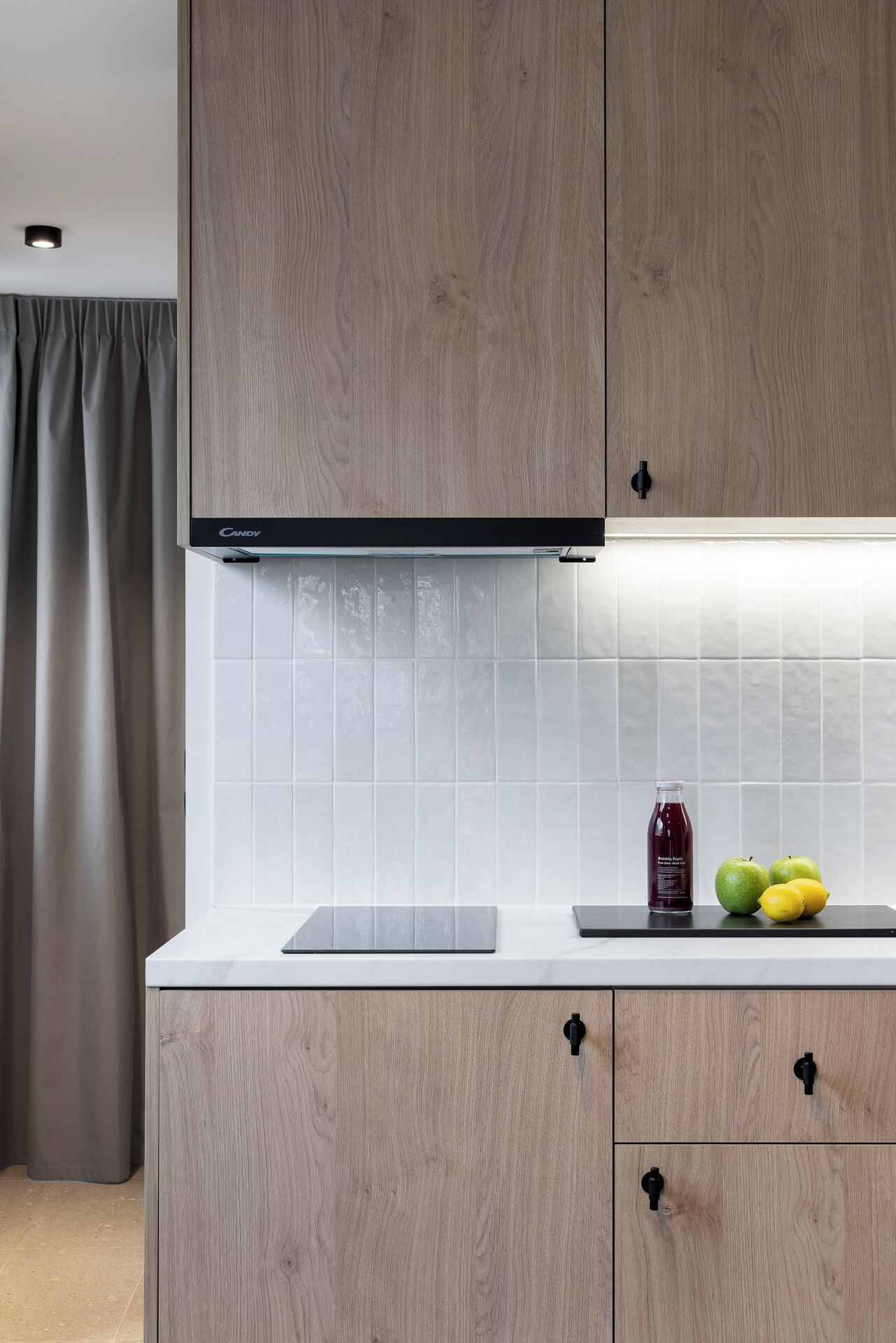 A modern kitchen with wooden cabinets, a white countertop, and a tiled backsplash.