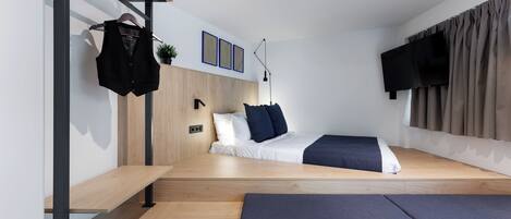A modern bedroom with a bed, bedside tables, a bench, a TV, and a window with curtains.