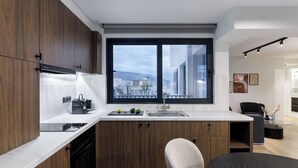 Eine moderne Küche mit großem Fenster, Holzschränken und einer schwarzen Arbeitsplatte.