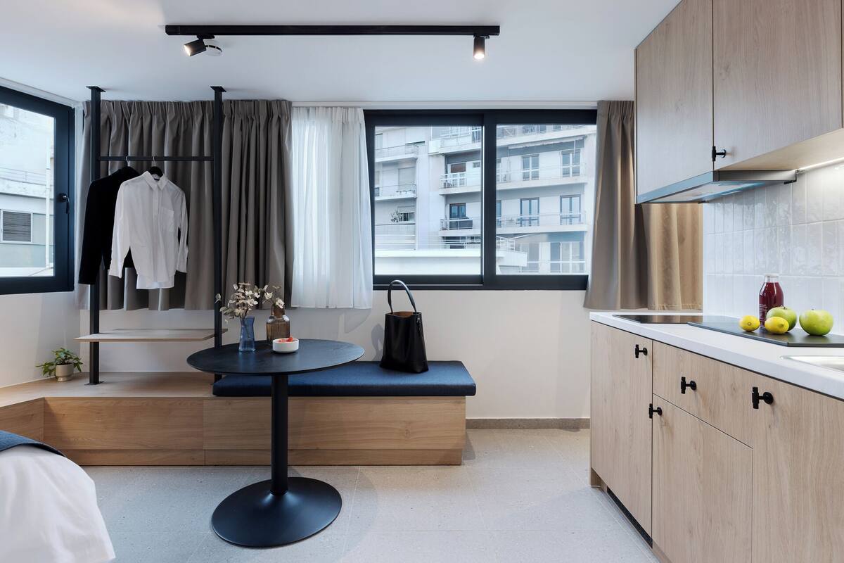 A modern kitchen with wooden cabinets, a round table, and a bench.