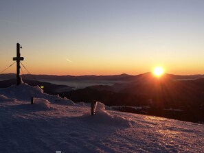 Un paysage enneigé, avec un coucher de soleil et des montagnes en arrière-plan.