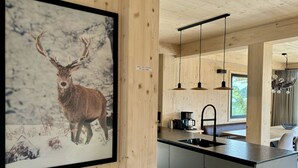 A modern kitchen with a wooden interior, a framed deer picture on the wall, and pendant lighting.