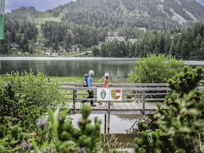 A wooden pier extending over a lake with two people walking.