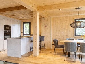 A modern kitchen with a central island, bar stools, and a dining table with chairs.