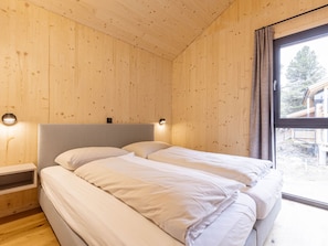 Ein Holzinnenraum mit einem Bett, Nachttischen und einem Fenster mit Blick.