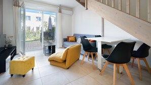 Un salon moderne avec un canapé, un pouf et un coin repas comprenant des chaises.