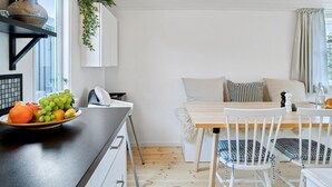 A modern kitchen with a wooden table, white cabinets, and a fruit bowl.