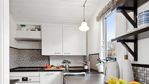 A modern kitchen with white cabinets, a black countertop, a built-in oven, and a window with a view.