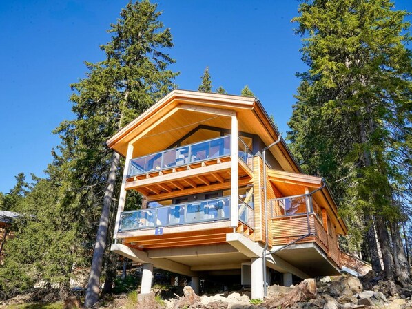 Perched in a forested area, this cabin offers expansive views from its upper-level balcony.