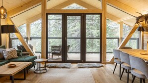 A spacious loft with a high ceiling, large windows, a dining area, and a cozy seating space. - 02_NTH019_Sup Chalet mit Sauna und Hot Tub 2 Etage by Interhome (Turracher Höhe)