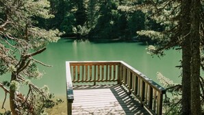 A wooden deck leading to a calm lake surrounded by dense forest. - 02_NTH019_Sup Chalet mit Sauna und Hot Tub 2 Etage by Interhome (Turracher Höhe)
