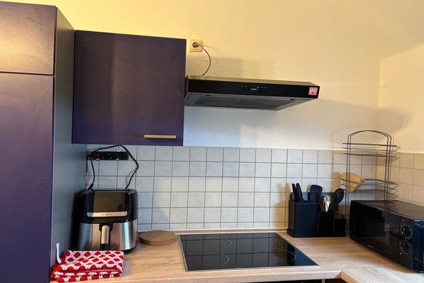 A modern kitchen with a built-in oven, microwave, and induction cooktop.