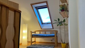 A room with a sloped ceiling, a wooden bunk bed, a small window, a floor lamp, and a potted plant. - Airy City Apartment in Zwickau (Zwickau)