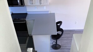 A staircase leading to a kitchen area with a modern design, including a white countertop and a black chair. - Charming 3-bedroom townhome with AC, WiFi in serene Ewa Beach (Ewa Beach)