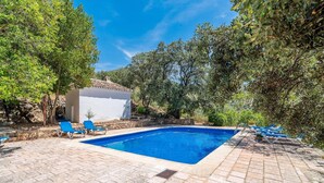 Une piscine rectangulaire aux carreaux bleus, entourée de carreaux de pierre et de chaises longues bleues.