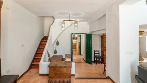 Un escalier avec une rampe en bois mène à un coin repas où se trouvent une table et des chaises en bois.