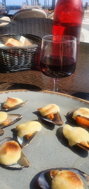 A table with a plate of food, a glass of red wine, and a wicker basket.