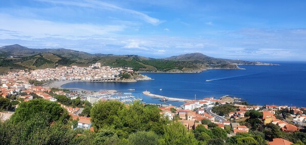 A coastal town with a marina, a bridge, and a mountainous backdrop.