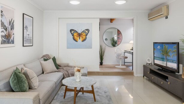 Ein modernes Wohnzimmer mit einer Couch, einem Couchtisch, einem Fernseher und Kunstwerken an den Wänden.