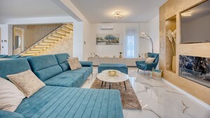 A modern living room with a blue sofa set, a coffee table, and a fireplace.