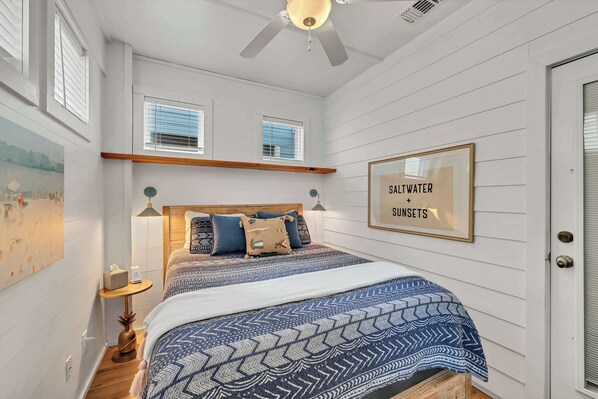 A bedroom with a bed, a ceiling fan, a framed sign, and a window. - Shared Pool * 4BR * w/ golf cart * In town & beach (Port Aransas)