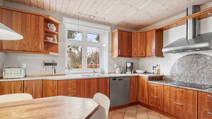 A modern kitchen with wooden cabinets, a granite countertop, and a built-in dishwasher. - "Kerttuli" - 540m from the sea by Interhome (Væggerløse)