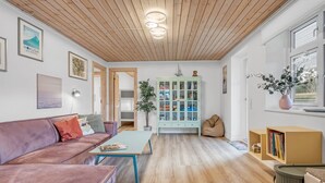 A cozy living room with a wooden ceiling, a green cabinet, a sofa, and a coffee table. - "Kerttuli" - 540m from the sea by Interhome (Væggerløse)
