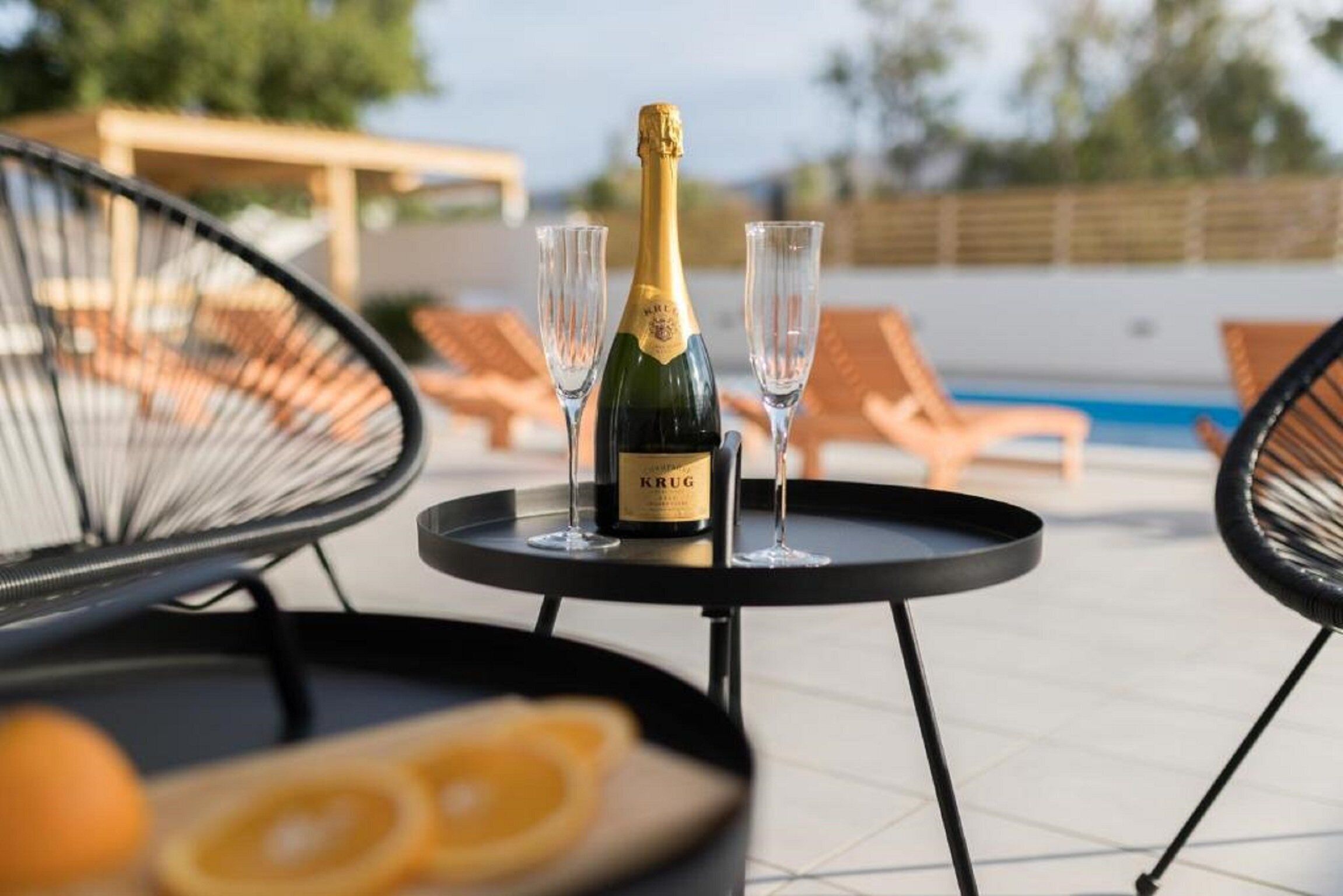 Une bouteille de champagne Krug sur une petite table, accompagnée de deux verres, le tout entouré de fauteuils confortables.