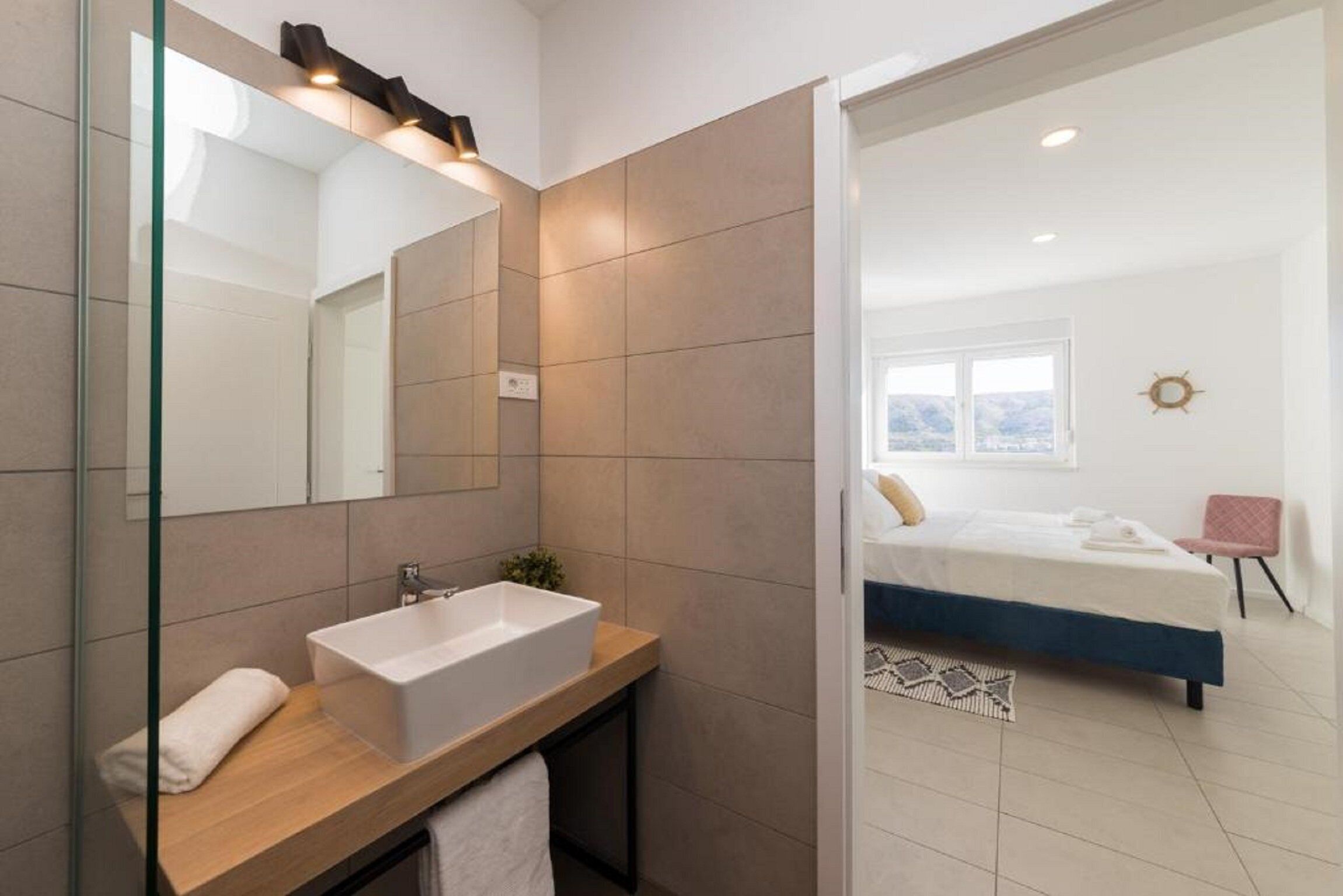 Une salle de bain moderne avec un grand miroir, un meuble-lavabo en bois et une baignoire blanche.