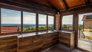 Eine Küche mit Holzschränken und großen Fenstern mit Blick ins Grüne.
