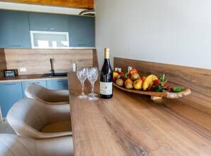Eine moderne Küche mit Holzarbeitsplatte, einer Weinflasche, zwei Gläsern und einer Obstschale.