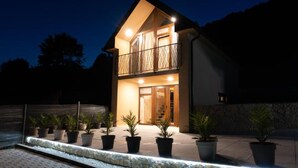 Ein zweistöckiges Haus mit Balkon, Blumentöpfen und einer Steinmauer.