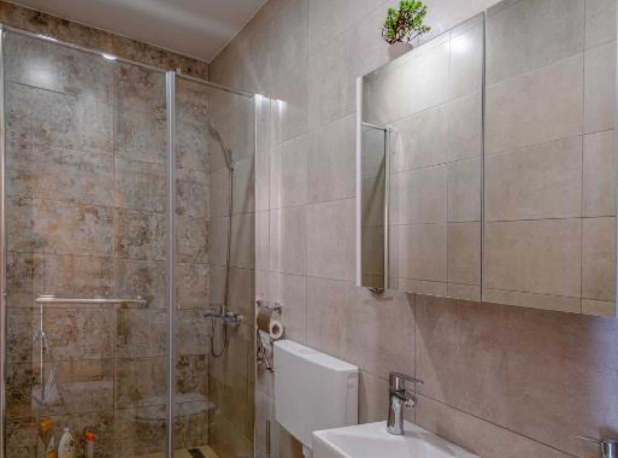 A bathroom with a glass shower enclosure, a white sink, and a mirror above it.