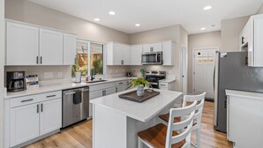A modern kitchen with white cabinetry, a central island, a built-in microwave, and a stainless steel refrigerator. - New House! Close to HPU & HPMKT (High Point)