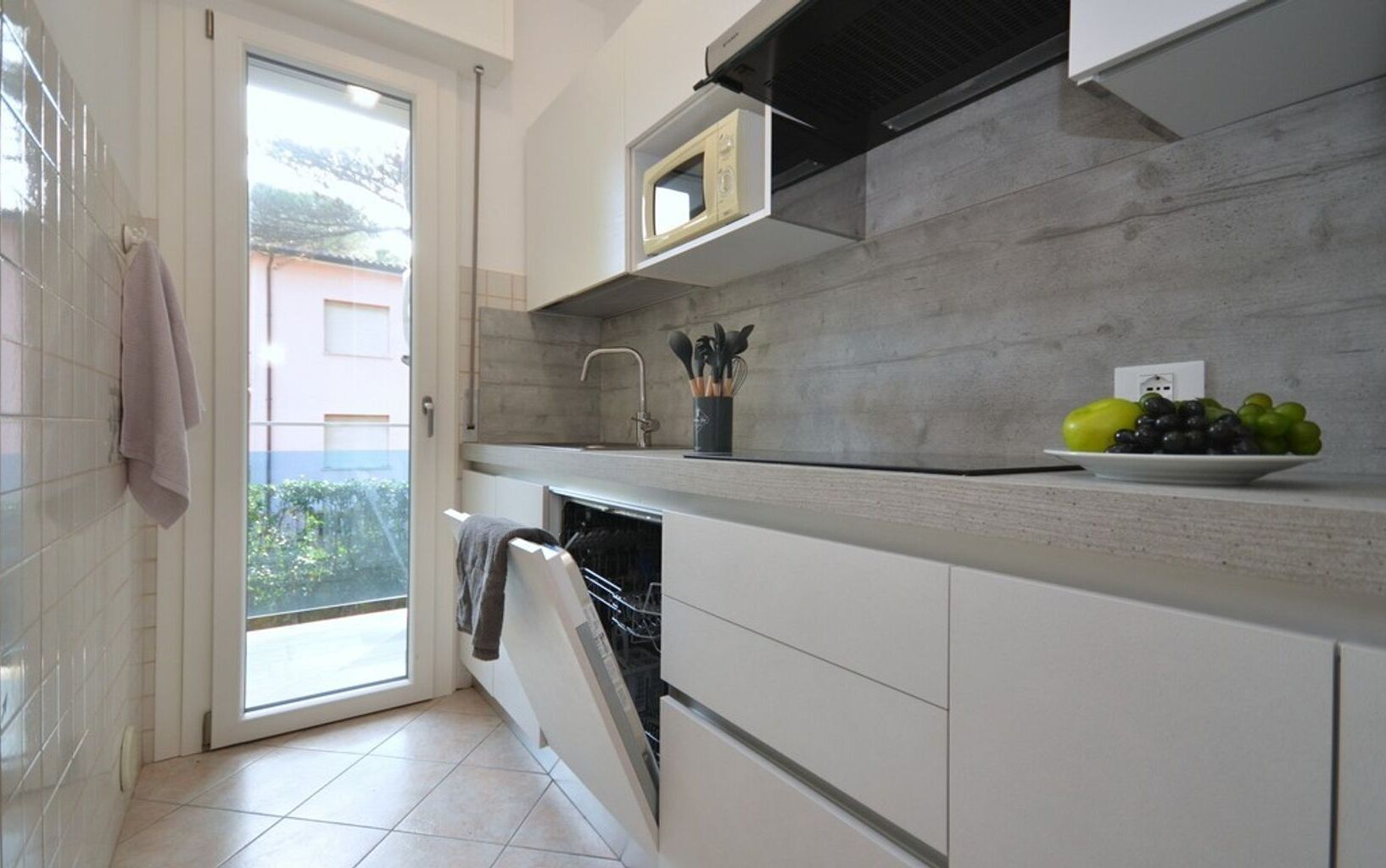 A modern kitchen with white cabinets, a built-in microwave, and a dish rack.