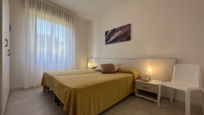 A hotel room with a bed, bedside tables, a chair, and a painting on the wall.