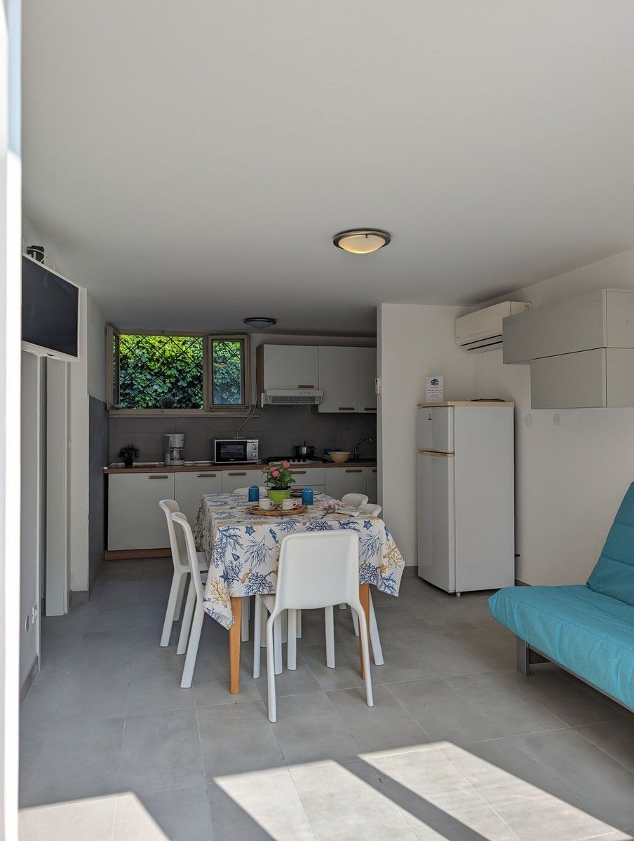 Una cocina compacta con armarios blancos, una mesa de comedor con sillas y un sofá azul.