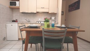Una cocina compacta con una mesa de comedor, sillas, microondas, refrigerador y cafetera.