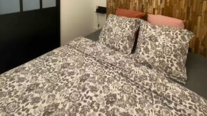 Un dormitorio con cama, cabecera de madera y lámpara moderna.