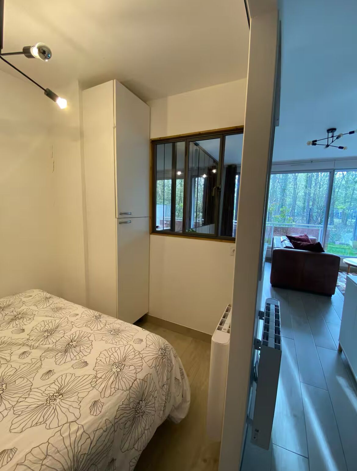 Ein Schlafzimmer mit Bett, Kleiderschrank, Fenster und Blick ins Freie.