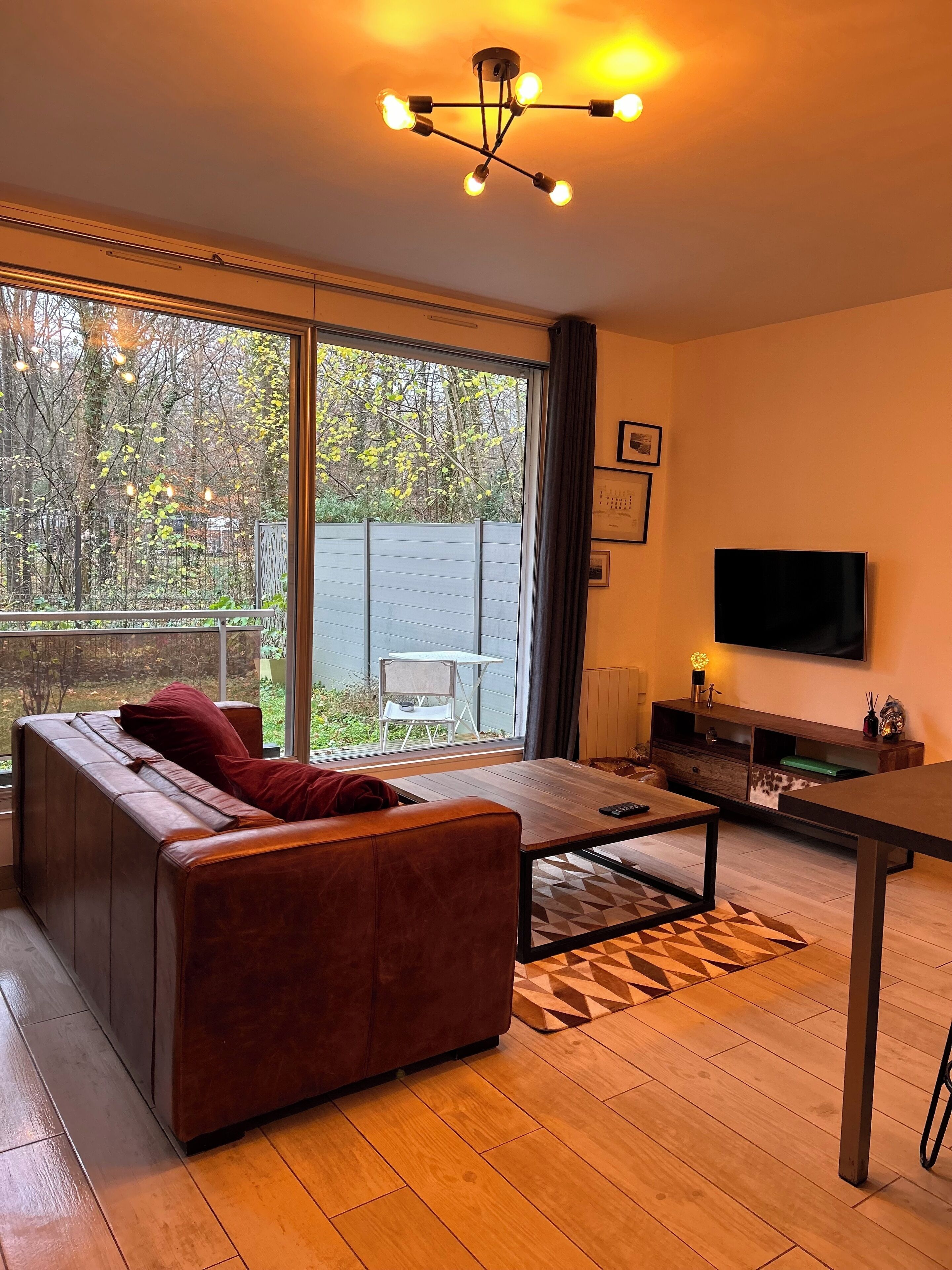 A modern living room with a large window, a sofa, a coffee table, and a TV.
