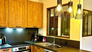 Una cocina moderna con armarios de madera, horno integrado, pileta de acero inoxidable y una barra con taburetes.