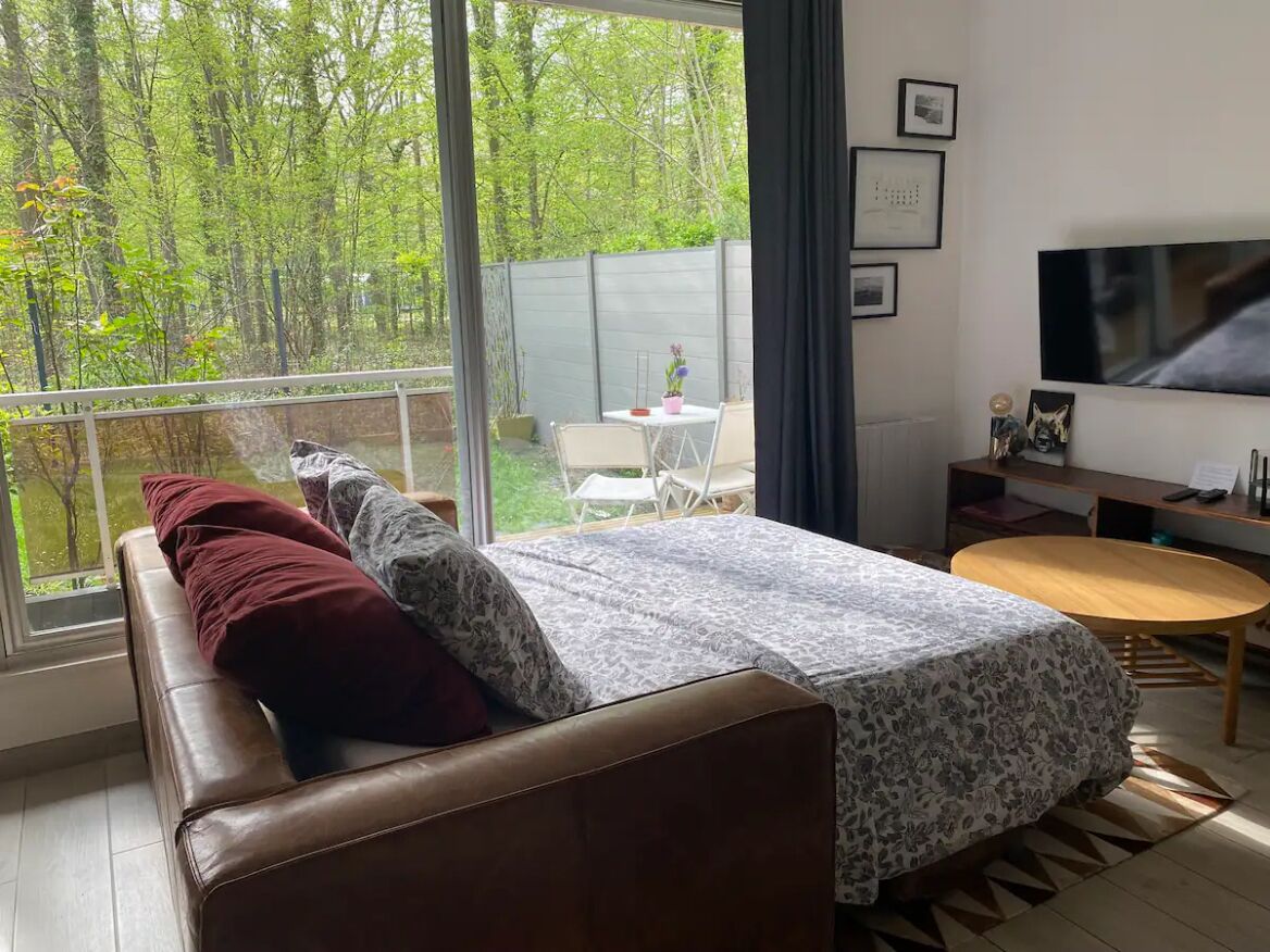 Ett modernt sovrum med ett stort fönster, en säng, en tv och ett litet bord.