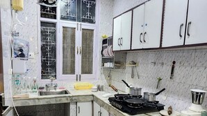 Una cocina con gabinetes blancos, un lavamanos, una estufa y una ventana con barandillas decorativas.