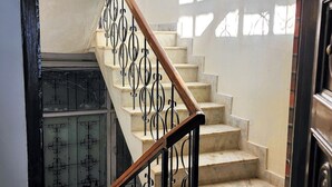 Una escalera con barandilla de madera y barandillas de metal negro, que conduce a un rellano con un cuadro enmarcado en la pared.
