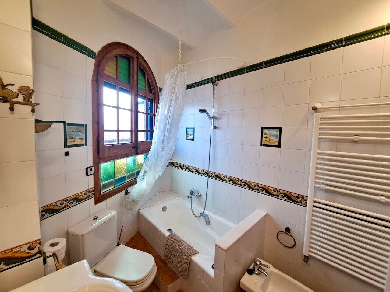Een badkamer met een bad, toilet en wastafel.